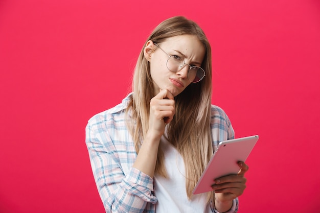 Mujer de negocios joven que sostiene la tableta y piensa