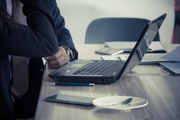 Mujer de negocios joven que trabaja en la computadora en café con el jefe