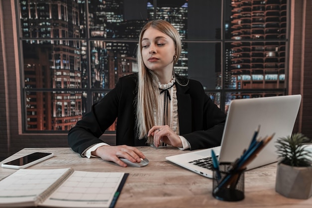 Mujer de negocios joven que trabaja con computadora y escribe en ntepad en la oficina