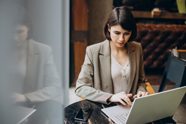 Mujer de negocios joven que trabaja en la computadora portátil en un café