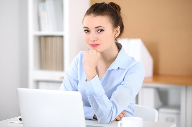 Mujer de negocios joven que trabaja en la computadora portátil en la oficina. Concepto de negocio exitoso.