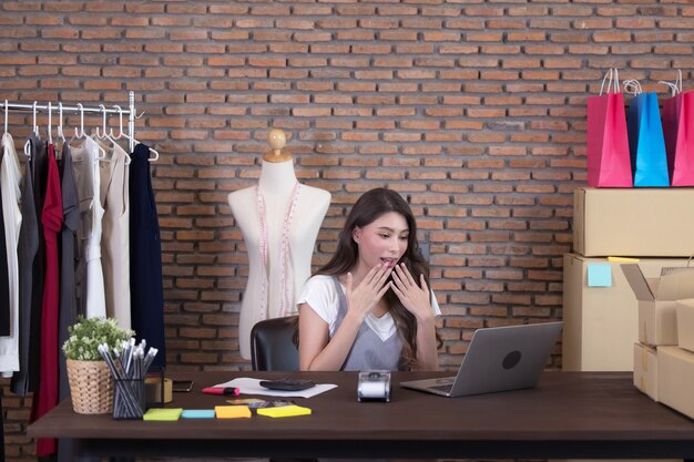 Mujer de negocios joven que trabaja vendiendo en línea. Cara de sorpresa y conmoción del éxito de la mujer asiática al hacer grandes ventas de su tienda en línea. Las compras en línea