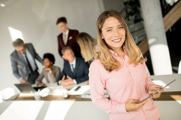 Mujer de negocios joven que usa la tableta digital en la oficina