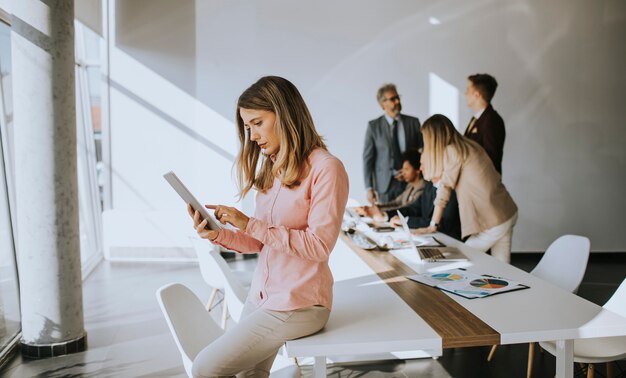 Mujer de negocios joven que usa la tableta digital en la oficina