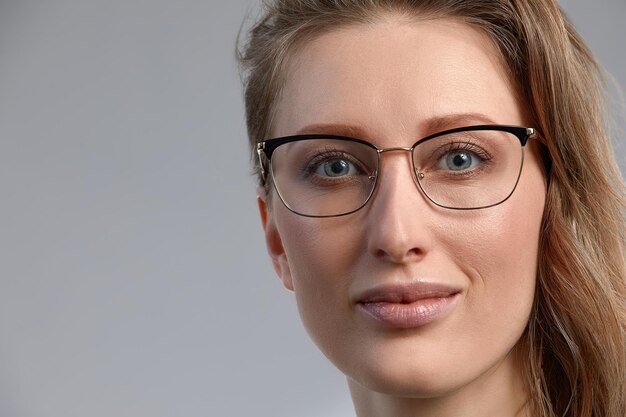 Mujer de negocios joven segura 3545 años de edad rubia elegante ropa formal y gafas fondo gris primer plano Concepto de éxito empresarial y profesional