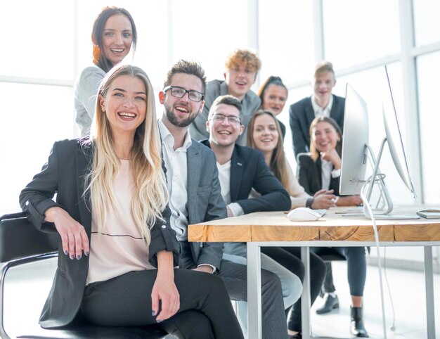 Mujer de negocios joven sentada frente a un gran equipo de negocios