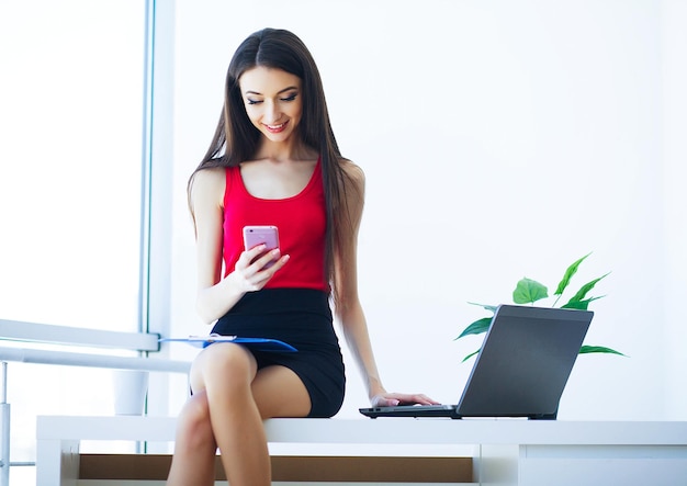 Mujer de negocios joven sentada en mesas y obras por computadora