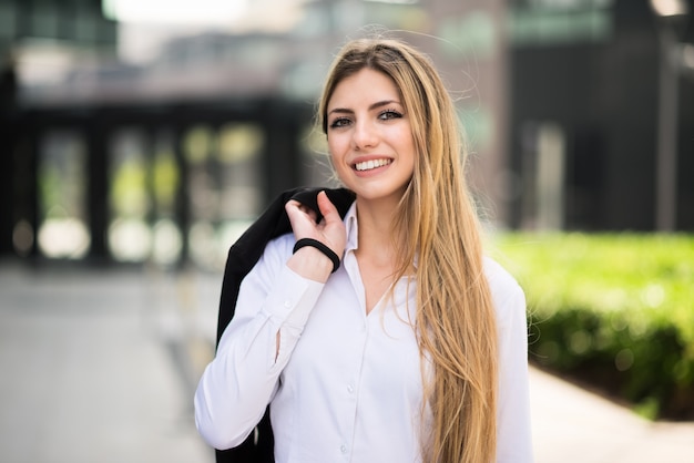 Mujer de negocios joven sonriente que camina al aire libre