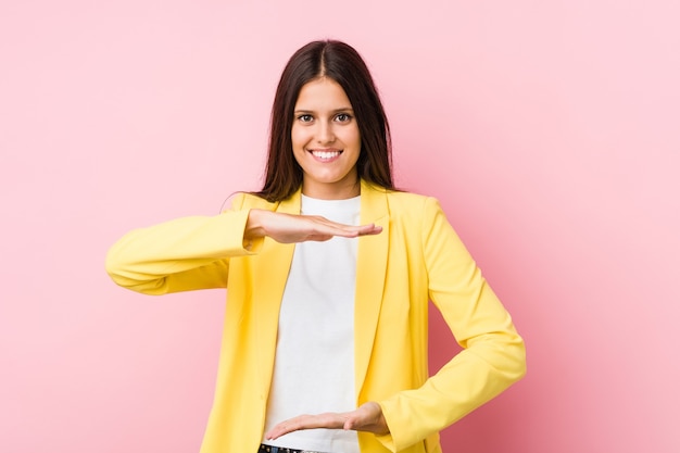 Mujer de negocios joven sosteniendo algo con ambas manos, presentación del producto.