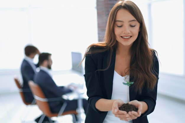 Mujer de negocios joven sosteniendo un brote fresco el concepto de una startup