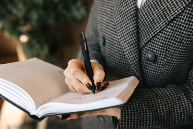 Mujer de negocios joven toma notas en un cuaderno en la oficina.