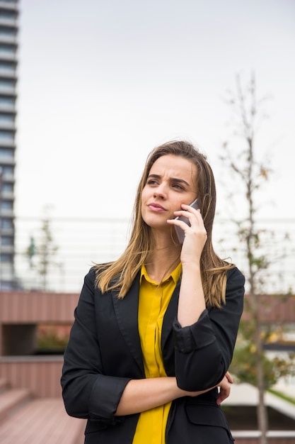 Mujer de negocios joven utiliza teléfono celular en la calle