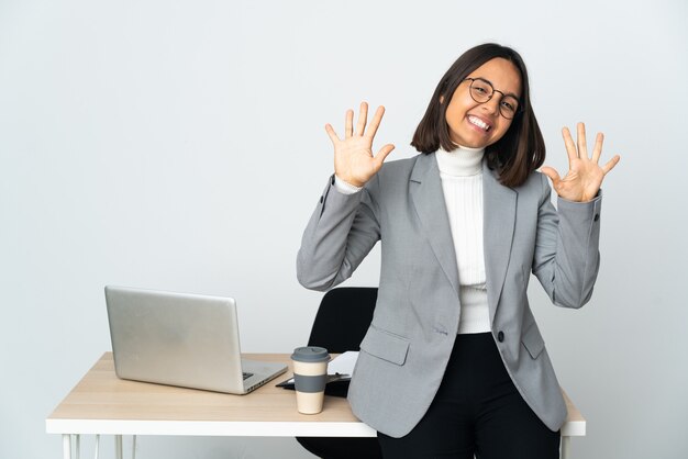 Mujer de negocios latina joven que trabaja en una oficina aislada en blanco contando diez con los dedos