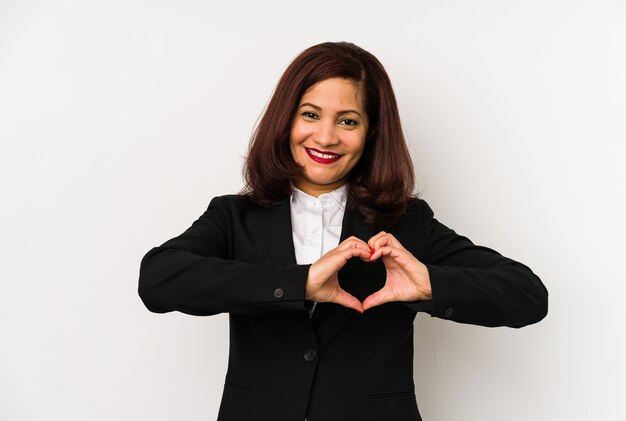 Mujer de negocios latina de mediana edad aislada sonriendo y mostrando una forma de corazón con las manos.