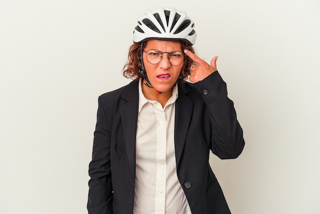 Mujer de negocios latina de mediana edad con un casco de bicicleta aislado sobre fondo blanco que muestra un gesto de decepción con el dedo índice.