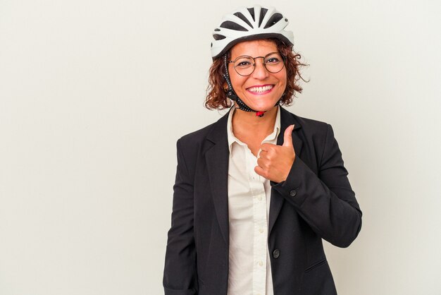 Mujer de negocios latina de mediana edad que llevaba un casco de bicicleta aislado sobre fondo blanco sonriendo y levantando el pulgar hacia arriba