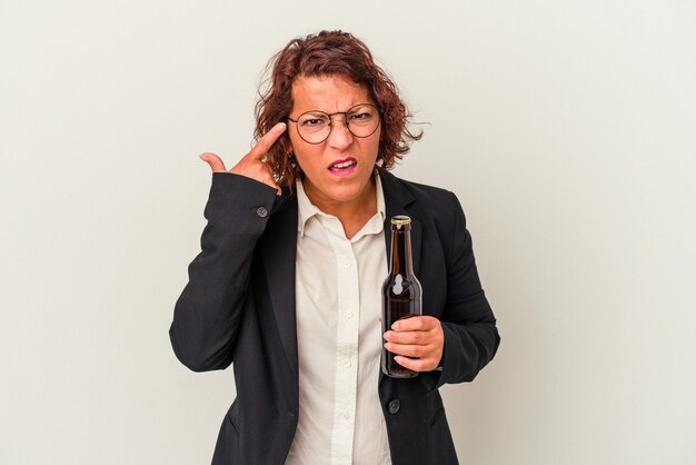 Mujer de negocios latina de mediana edad sosteniendo una cerveza aislada sobre fondo blanco mostrando un gesto de decepción con el dedo índice.