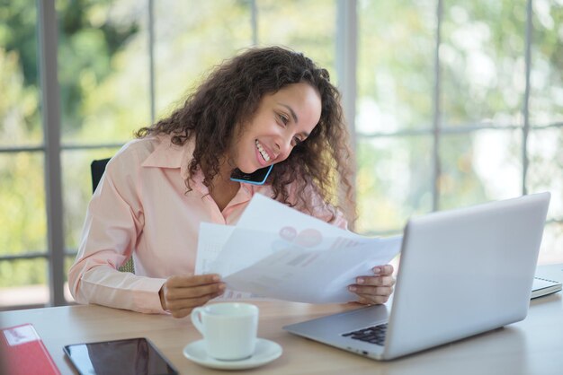 Mujer de negocios latina que trabaja felizmente en la oficina.