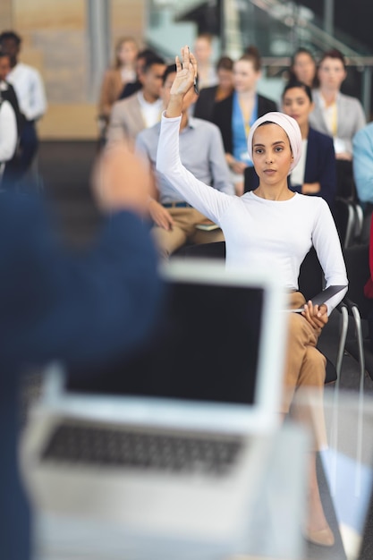 Foto mujer de negocios levantando la mano en un seminario de negocios