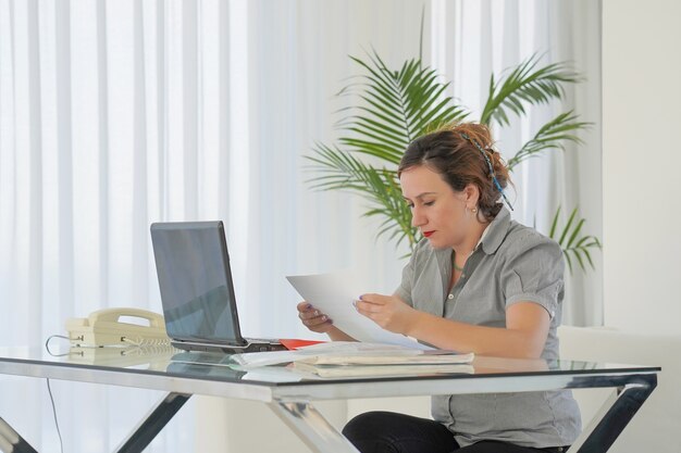 Mujer de negocios leyendo un documento en el espacio de trabajo de oficina.