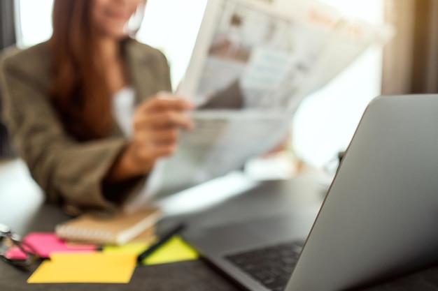 Una mujer de negocios leyendo el periódico mientras trabajaba en la oficina.