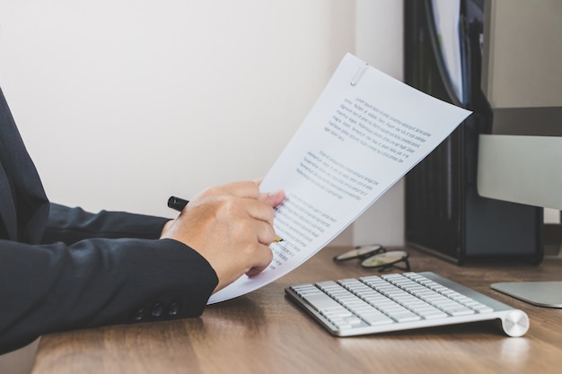 Mujer de negocios leyendo y revisando documento sobre su espacio de trabajo