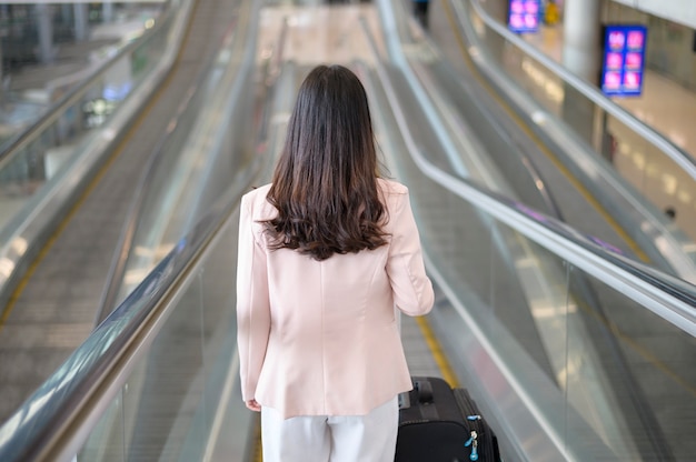 Una mujer de negocios lleva una máscara protectora en el aeropuerto internacional, viaja bajo la pandemia de Covid-19, viajes de seguridad, protocolo de distanciamiento social, nuevo concepto de viaje normal