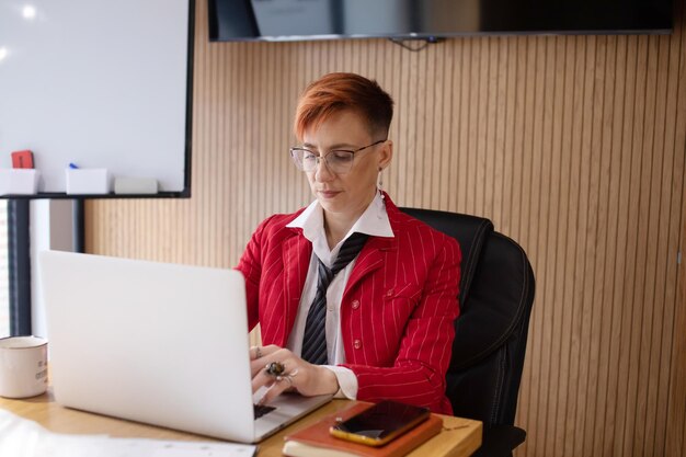 Mujer de negocios madura feliz empresaria en la oficina usando portátil en el trabajo