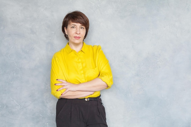 Mujer de negocios madura seria en retrato de camisa amarilla