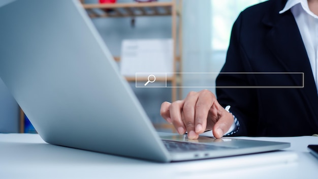 Mujer de negocios mano trabajando en la computadora y icono de búsqueda El concepto de buscar información de la red de Internet