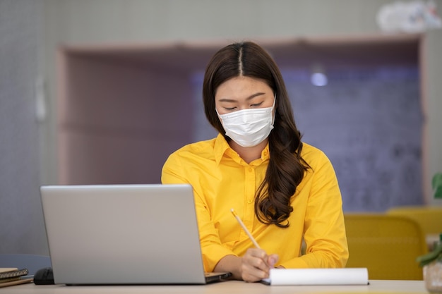 Mujer de negocios con máscara trabajando en la oficina