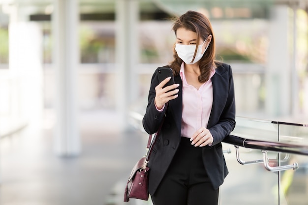 Mujer de negocios con máscara de vestir con teléfono.