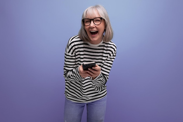 Mujer de negocios de mediana edad chateando en Internet usando un teléfono inteligente en un estudio brillante