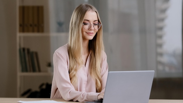 Mujer de negocios milenaria caucásica estudiante chica escritora periodista con gafas sentado