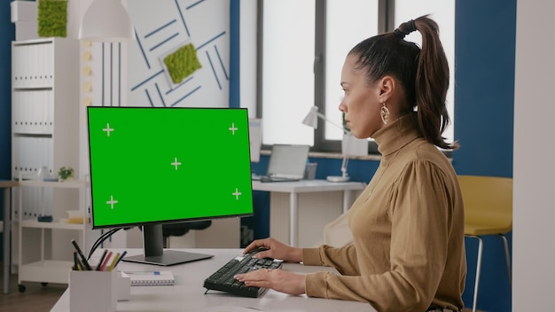 Mujer de negocios mirando la pantalla con pantalla verde, utilizando clave de croma con fondo aislado en la computadora. Empleado de la empresa que trabaja con maquetas de plantilla en blanco en la oficina. Copia espacio