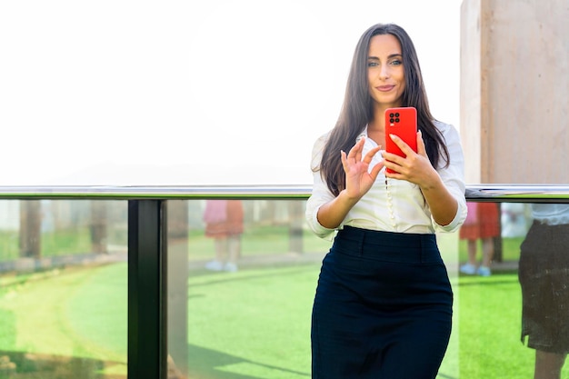 Mujer de negocios mirándote con el teléfono en la mano