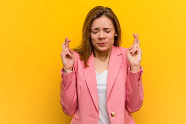 Mujer de negocios de moda joven cruzando los dedos para tener suerte