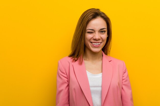 Mujer de negocios de moda joven guiñando un ojo, divertida, amigable y despreocupada.