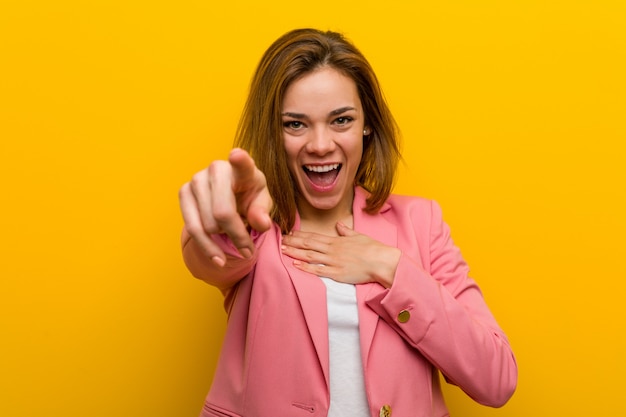 La mujer de negocios de moda joven señala con el dedo pulgar lejos, riendo y despreocupado.