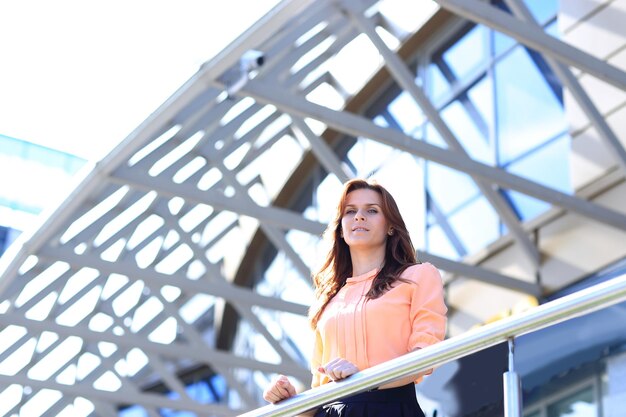 Mujer de negocios moderna de pie en el balcón de un edificio de oficinas moderno