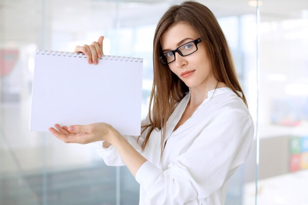 Mujer de negocios moderna de pie y guardando papeles en la oficina con espacio de copia