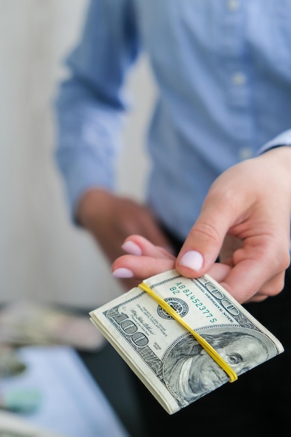 Foto mujer de negocios mostrando una difusión de dinero en efectivo en dólares de estados unidos de primer plano ingresos y concepto de negocio