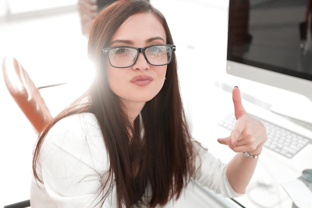 Mujer de negocios muestra un pulgar hacia arriba sentado en el concepto de éxito de escritorio