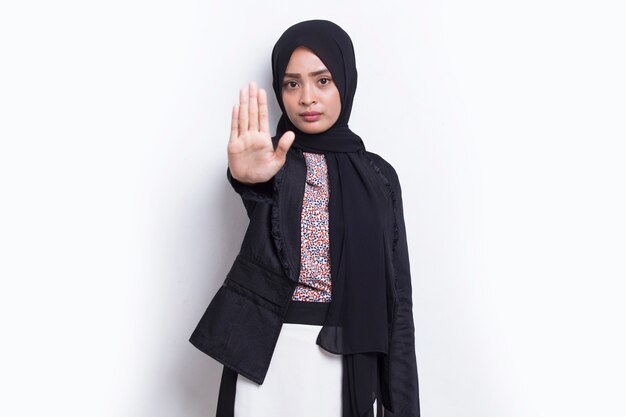 Mujer de negocios musulmana con la mano abierta haciendo señal de stop con gesto de defensa de expresión seria