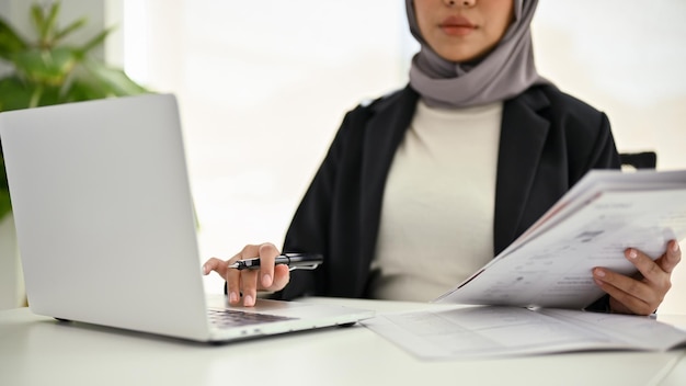 Mujer de negocios musulmana profesional que usa laptop analizando datos trabajando en su oficina