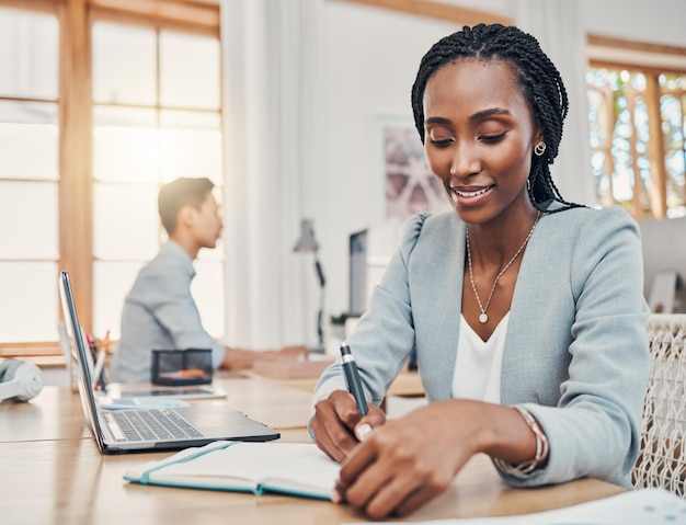 Mujer de negocios negra y escribiendo en un cuaderno para planificar el horario o la idea de trabajar en la oficina Empleada afroamericana feliz tomando notas para finanzas corporativas en el lugar de trabajo