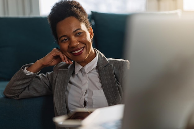 Mujer de negocios negra feliz que usa la computadora mientras trabaja en casa