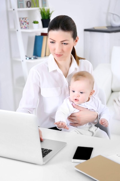 Mujer de negocios con un niño trabajando desde casa usando una laptop