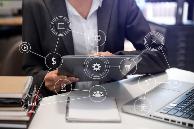 Foto mujer de negocios o diseñadora que usa teléfono móvil con computadora portátil y tableta digital y documento en el escritorio en la oficina con diagrama de red de iconos virtuales