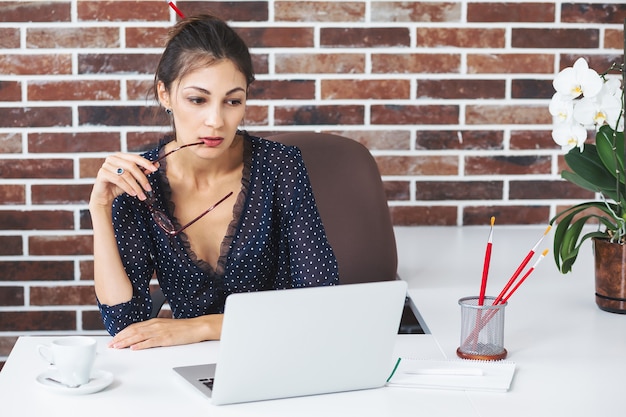 Mujer de negocios en la oficina en el escritorio con laptop pensando